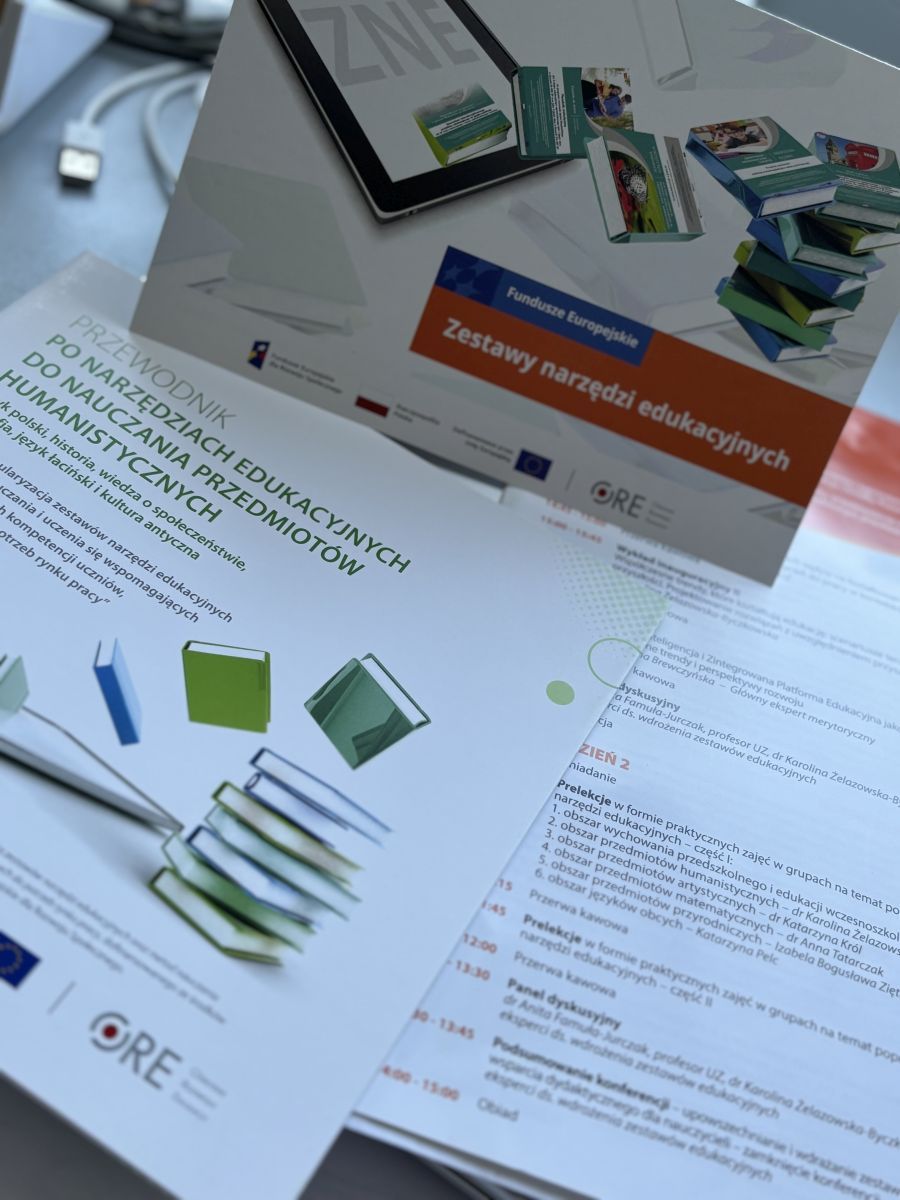Na zdjęciu są widoczne ulotki i foldery konferencyjne które są przewodnikami po narzędziach edukacyjnych wydanych w formie papierowej. Są na nich umieszczone ilustracje książek w kolorach zielonych i niebieskich oraz tytuły związane z tematyką konferencji ( zestawy narzędzi edukacyjnych) Widoczne jest też logo organizatora czyli Ośrodka Rozwoju Edukacji, logo Fudnuszy Europsjkich dla Rozwoju Społecznego oraz flaga Rzeczpospolitej Polskiej 